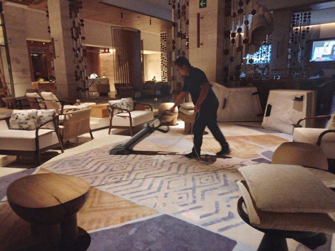 Colaborador aspirando la alfombra del lobby de un hotel