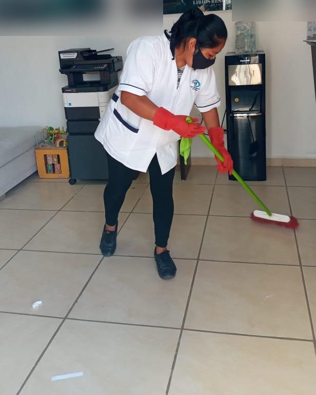 Colaboradora barriendo el piso de una recepción