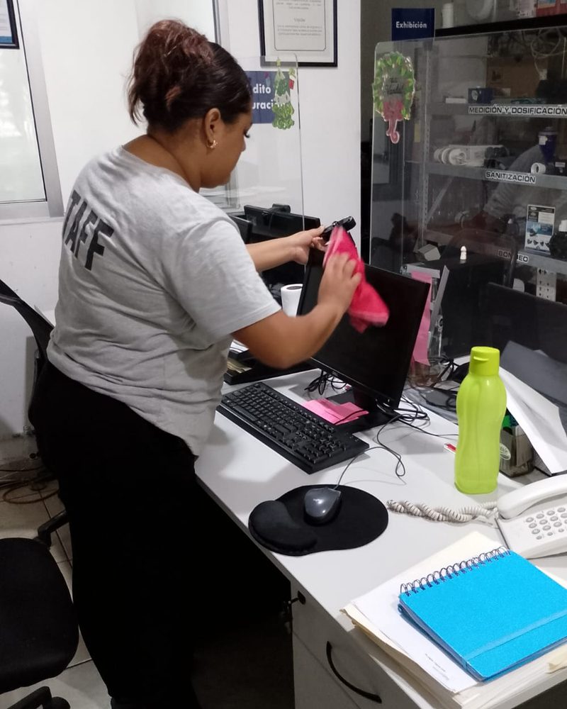 Colaboradora limpiando la pantalla de una computadora