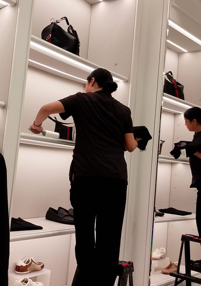 Colaboradora limpiando los anaqueles de exhibición de una boutique