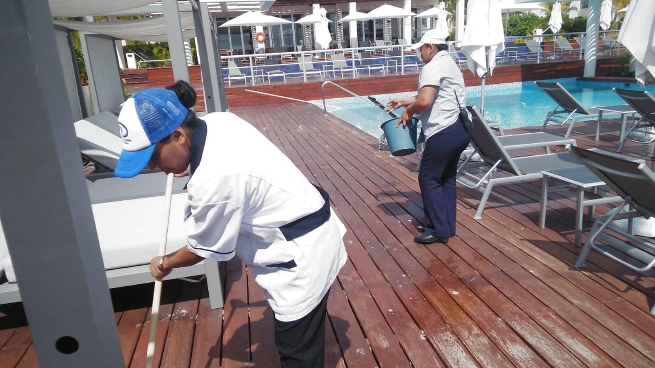 Colaboradoras lavando el deck de madera junto a la alberca